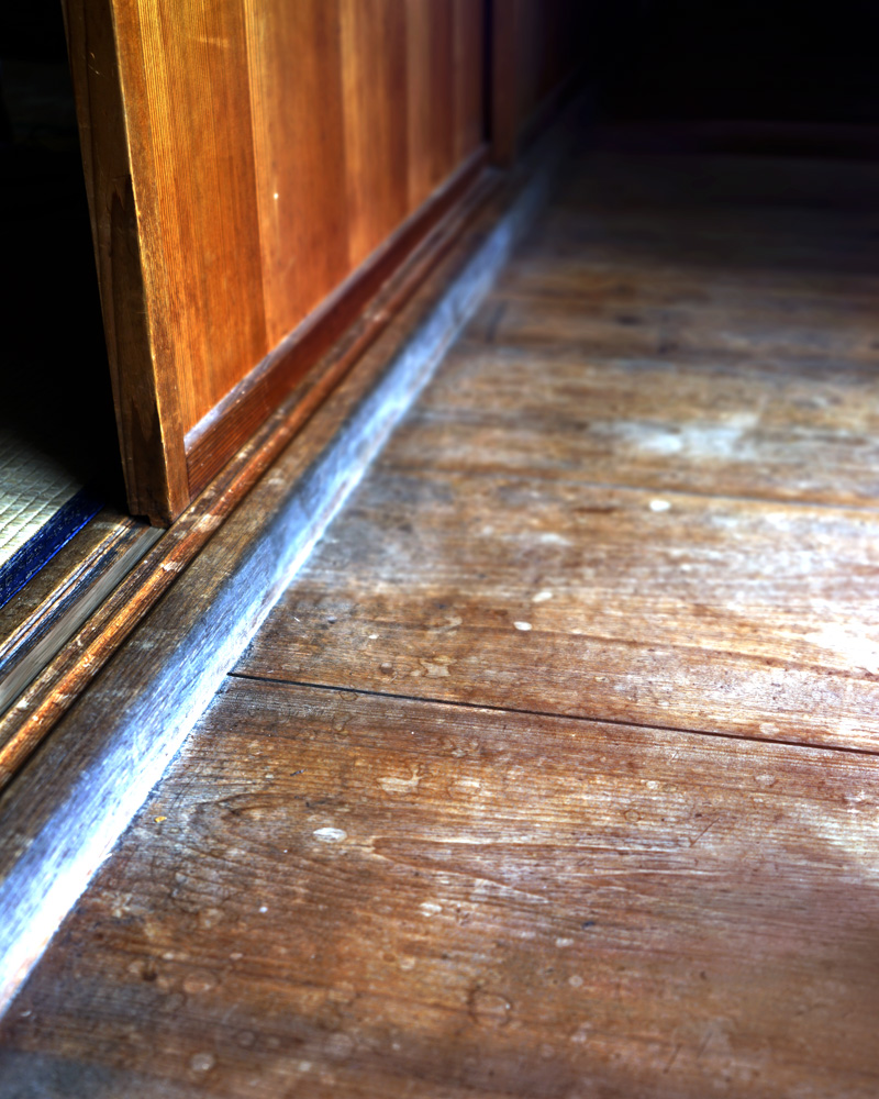 Close-up of an old wooden veranda floor in a quiet Japanese atelier, showing worn grain and aged texture